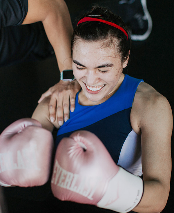 woman smiling ecstatically as she does a sit up with boxing gloves on