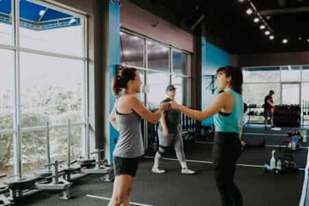 Two women give fist bumps in a gym
