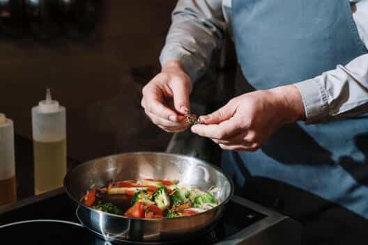 A man cooks vegetables on a stove top
