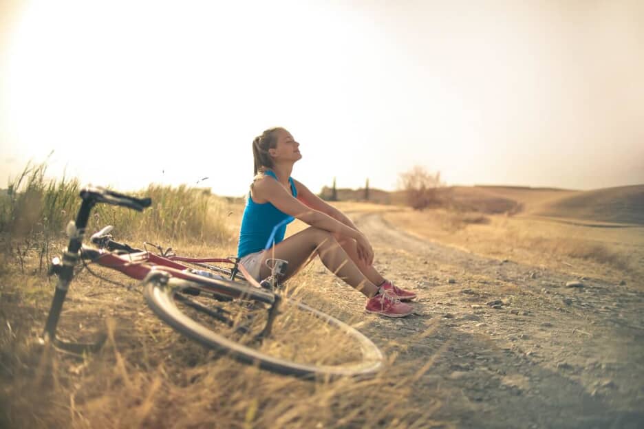 Woman rests on the ground next to her bike