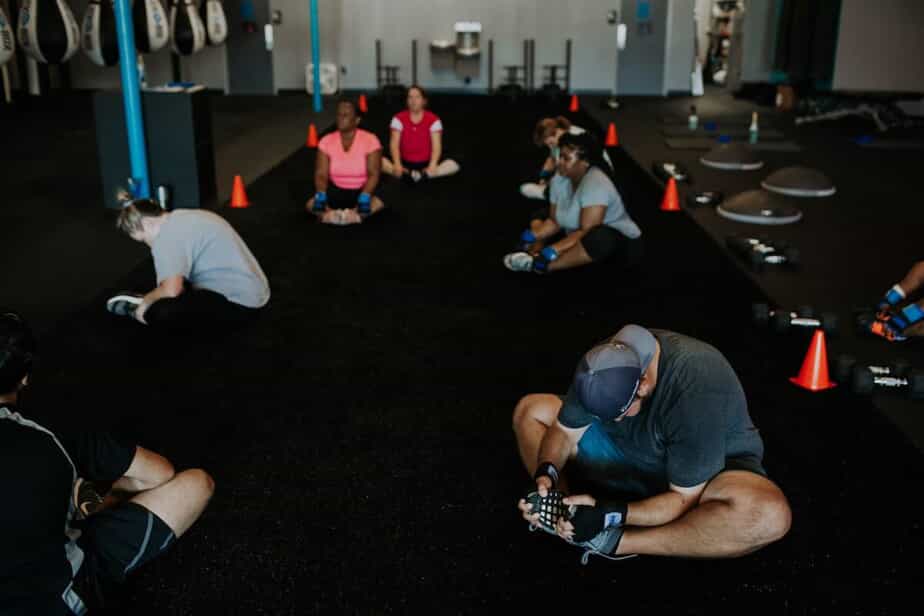 A group fitness class performs a stretch on the floor
