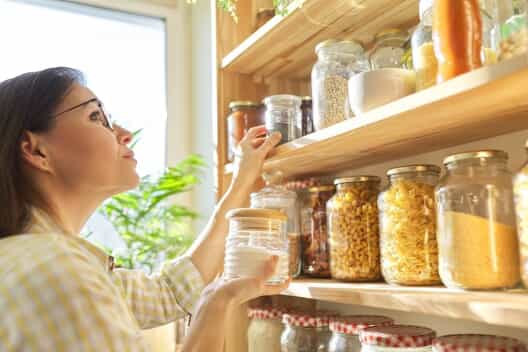 A woman organizes food in her pantry