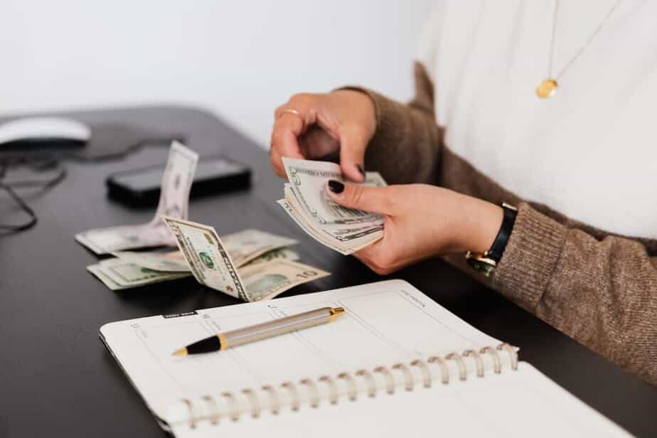 A woman counts money and writes in a planner