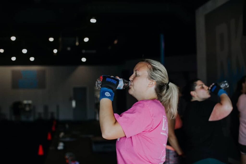 woman drinking water in the middle of her workout