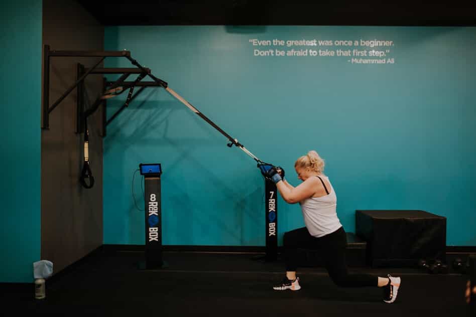 Woman performs a lunge using a TRX band