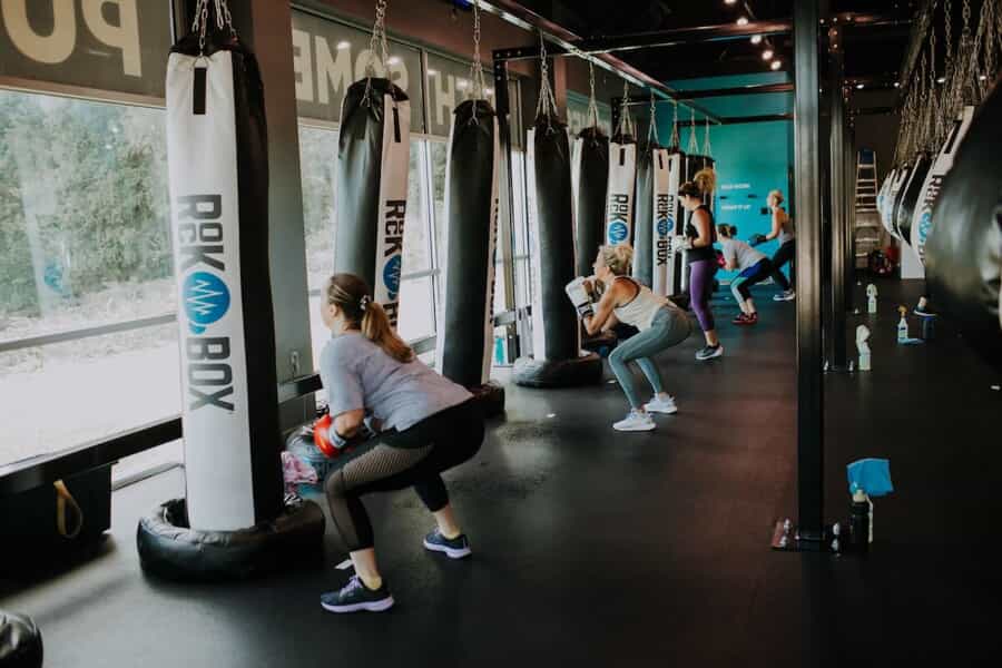 A group fitness class performs squats by punching bags