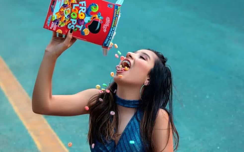 A woman pours Froot Loops cereal into her mouth