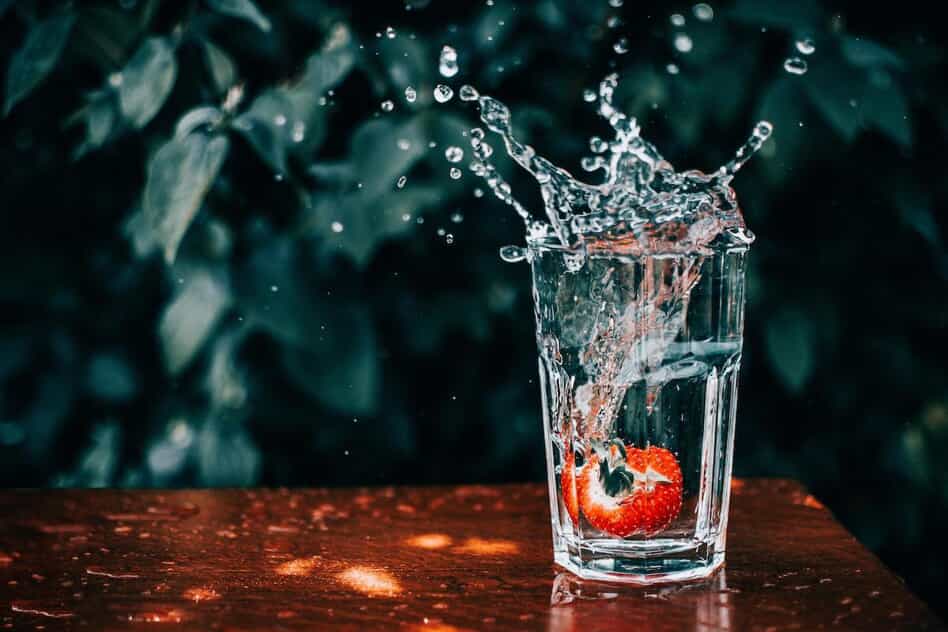 A glass of water with a strawberry inside