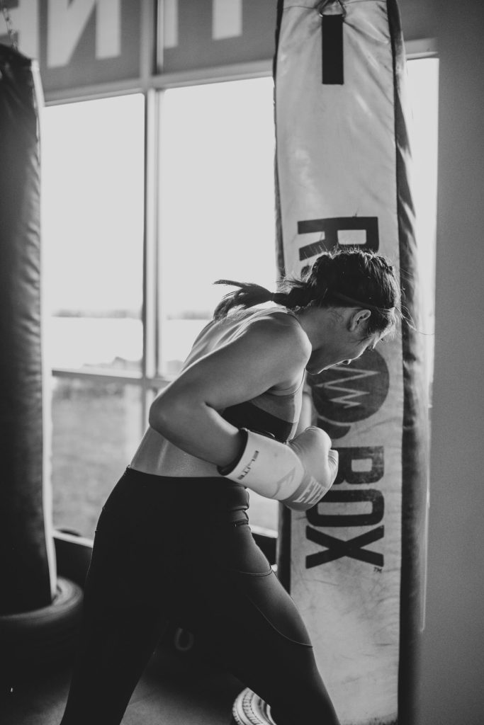 black and white image of a woman punching a boxing bag